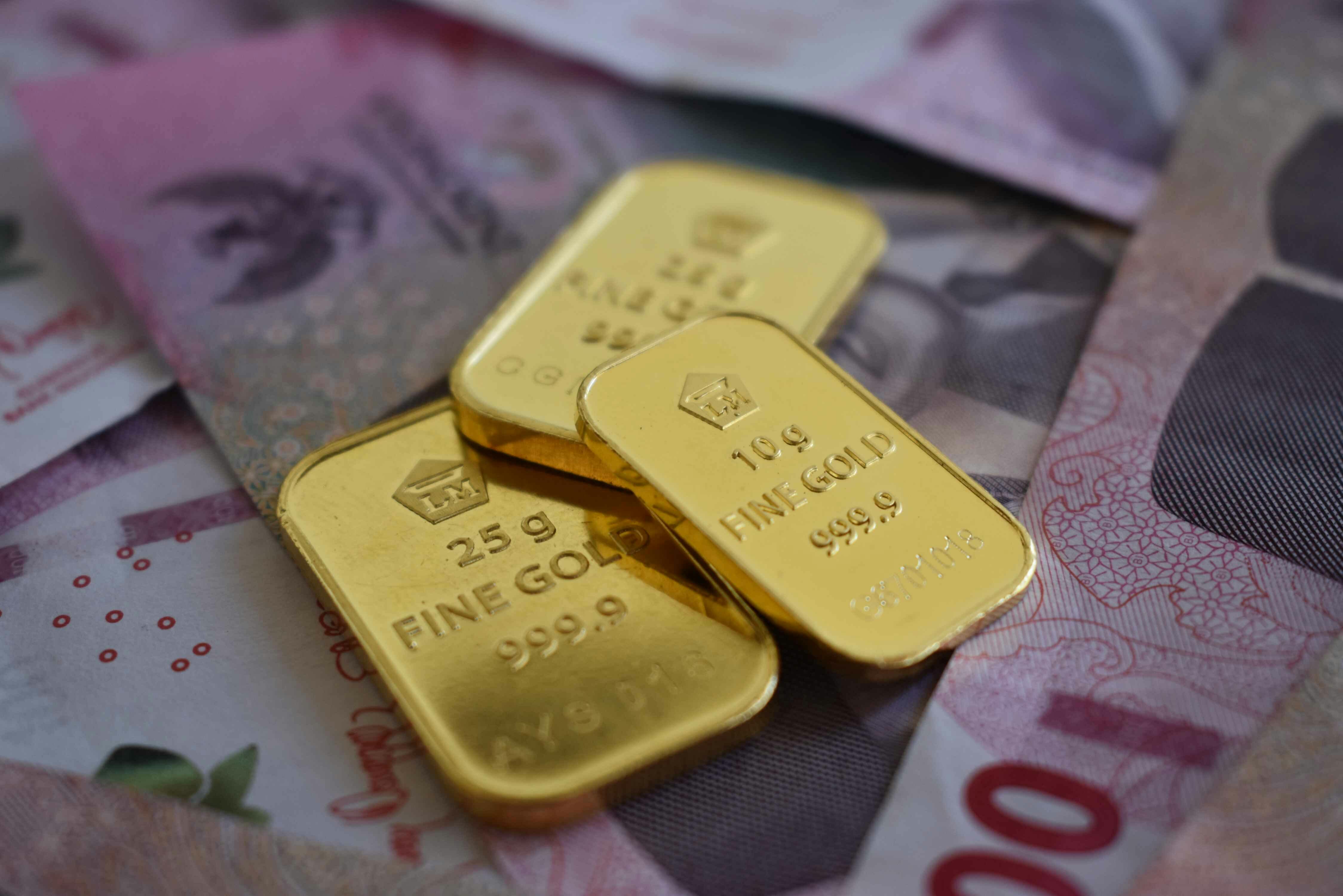 سبائك ذهبية فوق أوراق نقدية تعكس صراع الطلب على الملاذ الآمن مع قوة الدولار