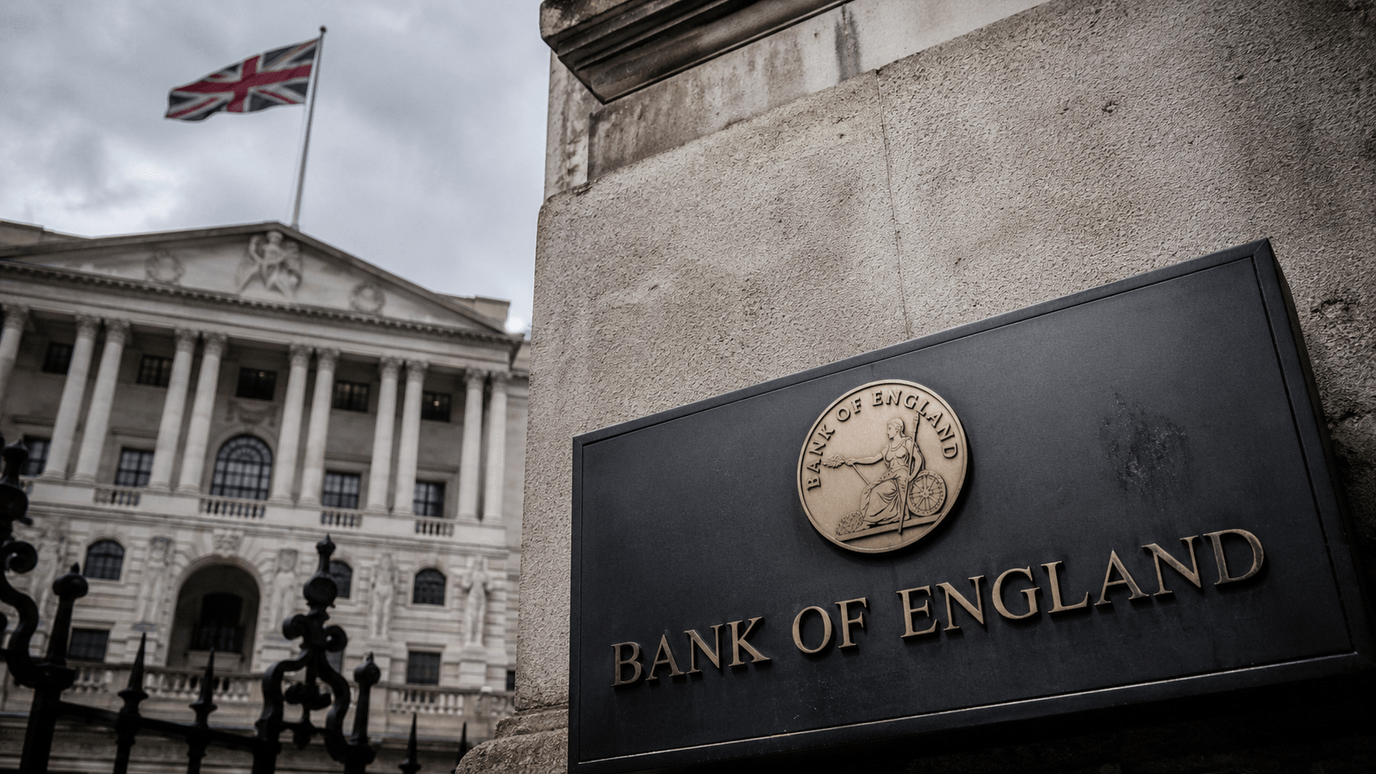 لافتة "BANK OF ENGLAND" النحاسيّة أمام واجهة بنك إنجلترا الكلاسيكيّة والعلم البريطانيّ — يوم قرار الفائدة